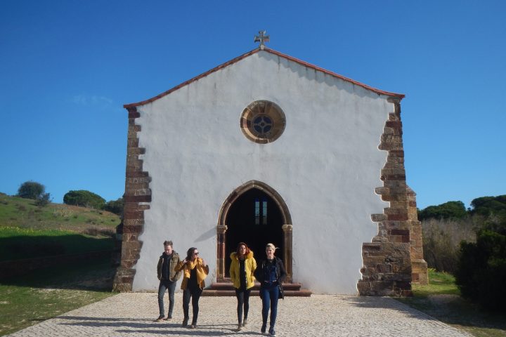 a group of people walking in front of a stone building