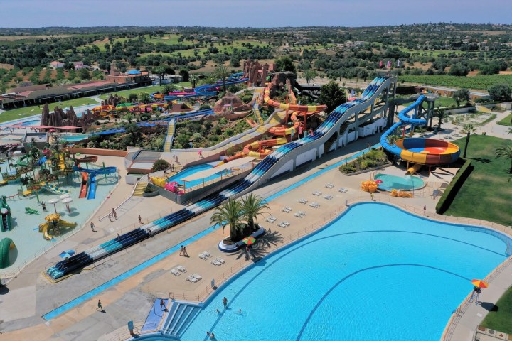 Aerial view of a large water park with multiple slides and pools on a clear day.