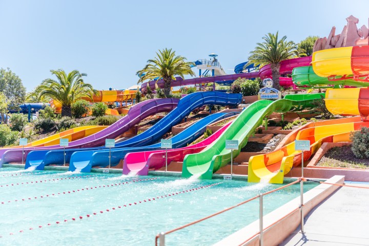 Colorful water slides at an outdoor water park with palm trees.