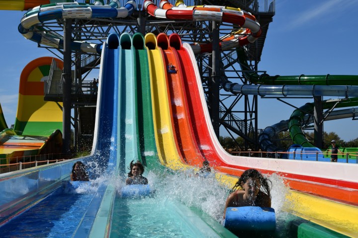 People sliding down colorful water slides at a water park on a sunny day.