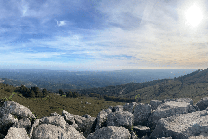 Panoramic mountain view with rocks, clear sky, and distant horizon.