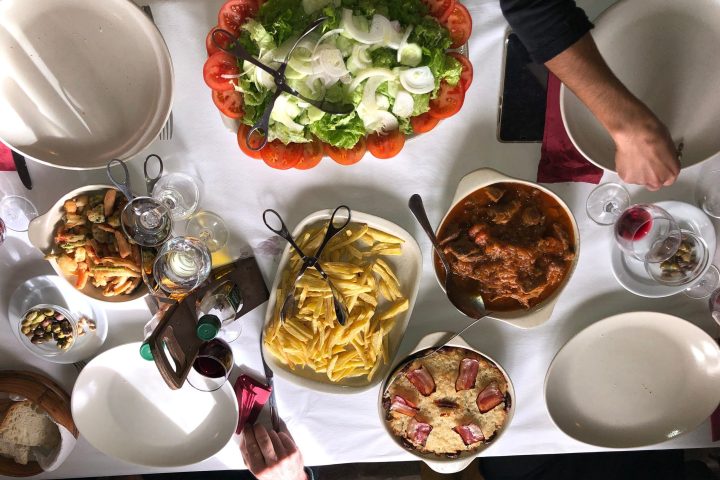 Top view of a table with assorted dishes including salad, meat stew, fries, and wine glasses.